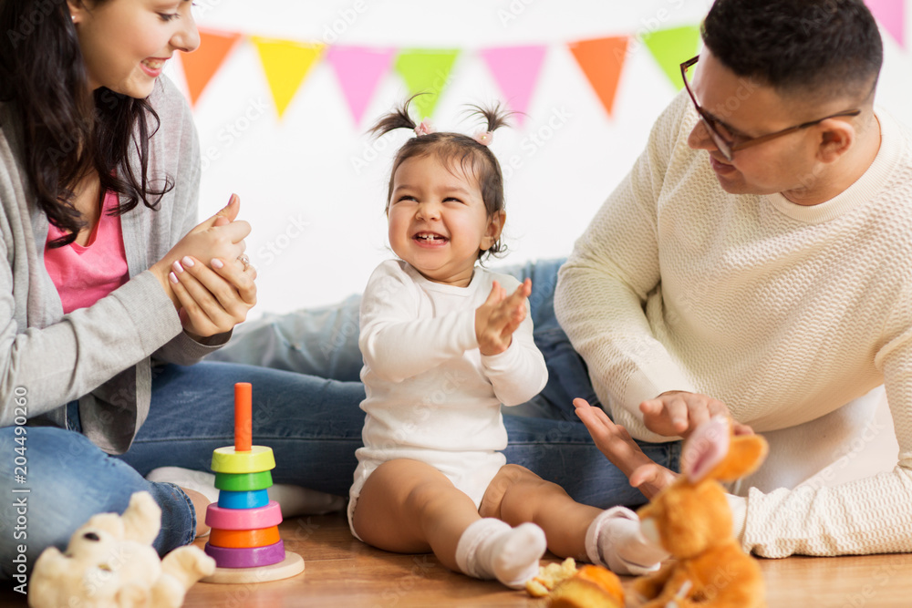family, holidays and people concept - happy mother, father and little daughter clapping hands on birthday party family, holidays and people concept - happy mother, father and little daughter clapping hands on birthday party