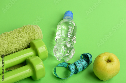 Dumbbells in bright green color, water bottle, measure tape, towel