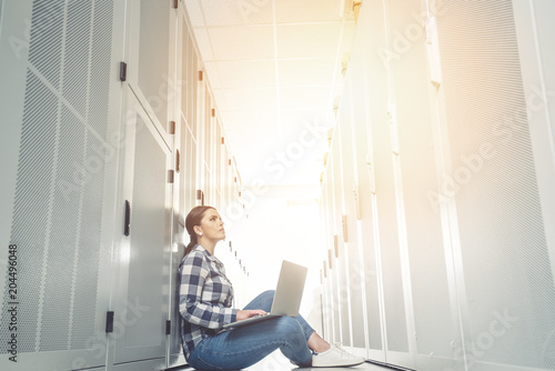 Woman technician working on and inspecting servers in server room