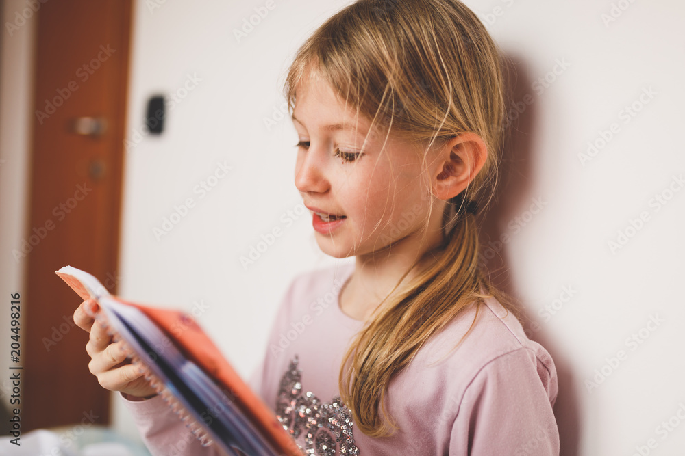 Young blond girl reading book, doing homework Young blond girl reading book, doing homework