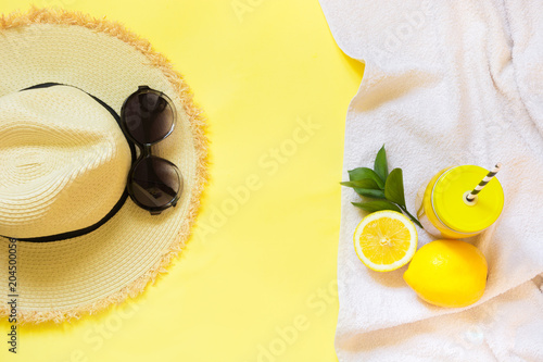Straw foman's hat, sun glasses and beach accessory with detox citrics water on yellow. Top view. Flat lay. photo