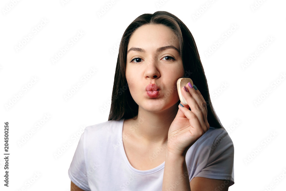 girl puts a foundation on her face with sponge looks at camera girl puts a foundation on her face with sponge looks at camera