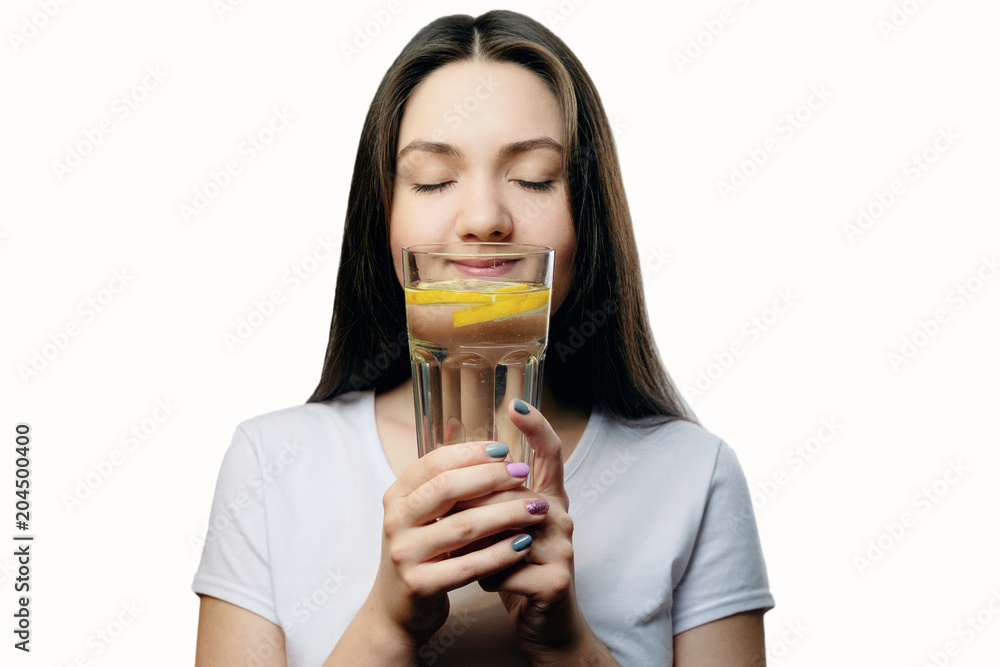 happy girl drinks water with lemon looks into a glass, sniffs smell concept of proper nutrition happy girl drinks water with lemon looks into a glass, sniffs smell concept of proper nutrition
