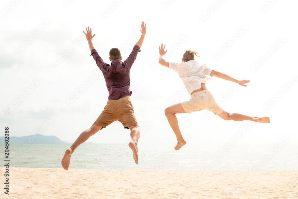 Young energetic happy tourist men jumping at the beach