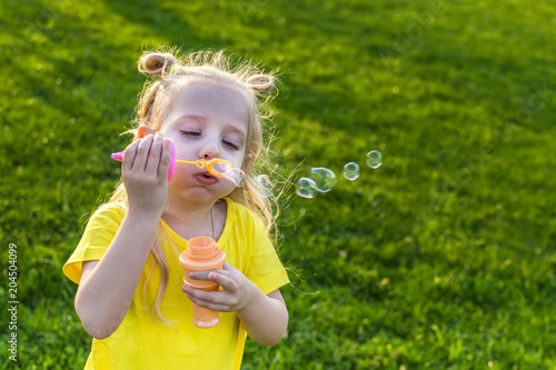 little girl lets the soap bubbles in the park. concept game with children