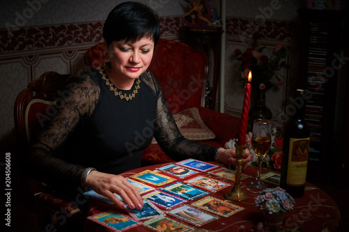 Fortune teller woman reading tarot cards in the dark room with a glass of wine