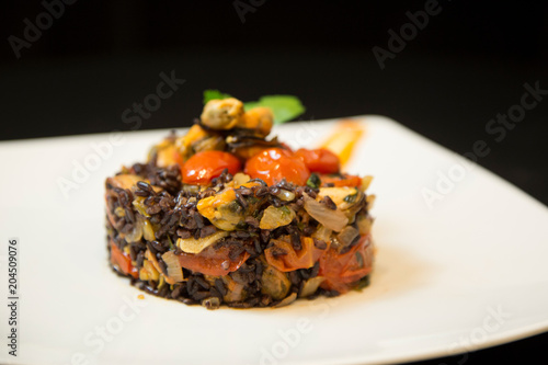 Assorted shellfish and mussels cooked with a venere rice on white dish photo