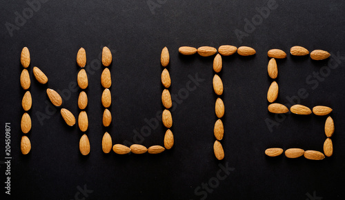 Text from nuts on a black background. Inscription  top view  almonds.