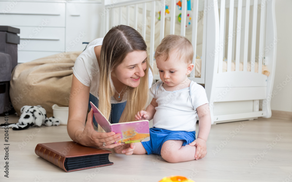 Adorable toddler boy sitting on floor with mother and reading book Adorable toddler boy sitting on floor with mother and reading book