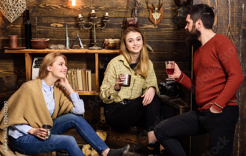 Family enjoy conversation in gamekeepers house. Friends  family spend pleasant evening  interior background. Sincere conversation concept. Girls and man on happy faces hold metallic mugs  talking