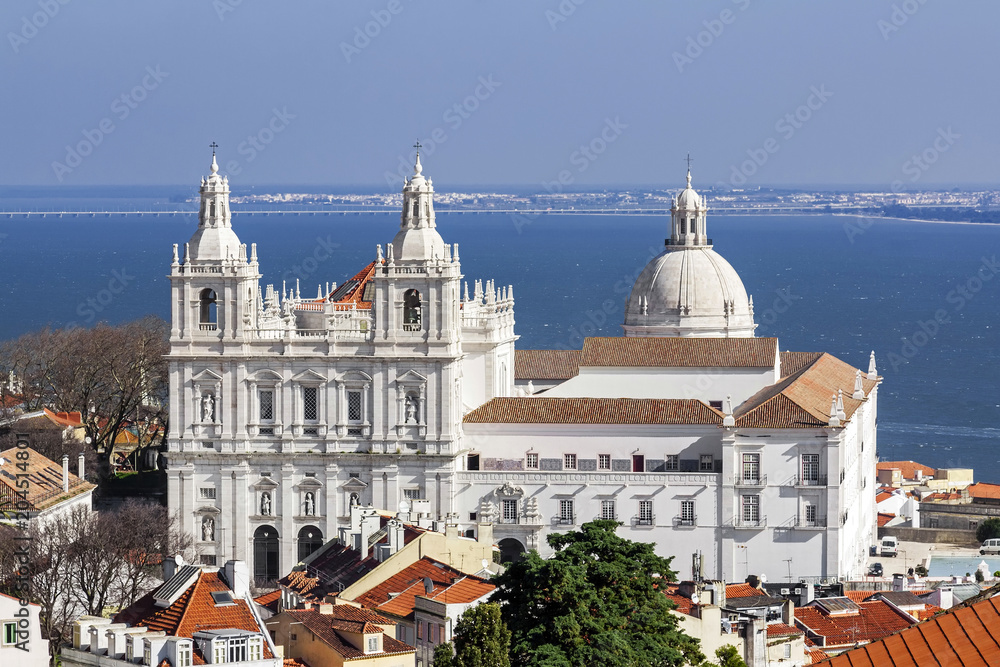 Sao Vicente de Fora Monastery, Alfama District orange rooftops and Tagus River estuary. Lisbon, Portugal.