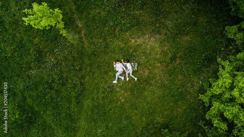 Above view of young couple holding hands while lying on the grass like running. Summer fun photo