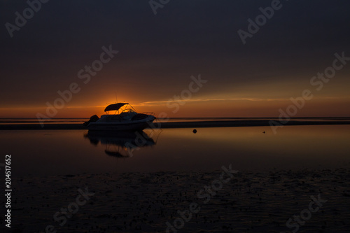 Boat in shallow water with sunset