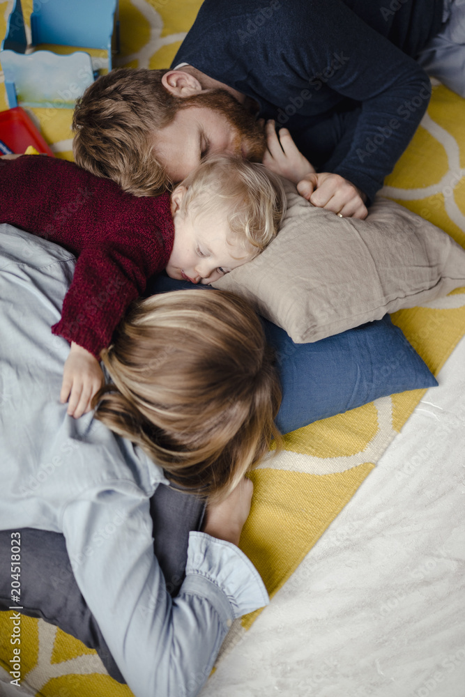 Tiered family resting together on the floor after playing Tiered family resting together on the floor after playing