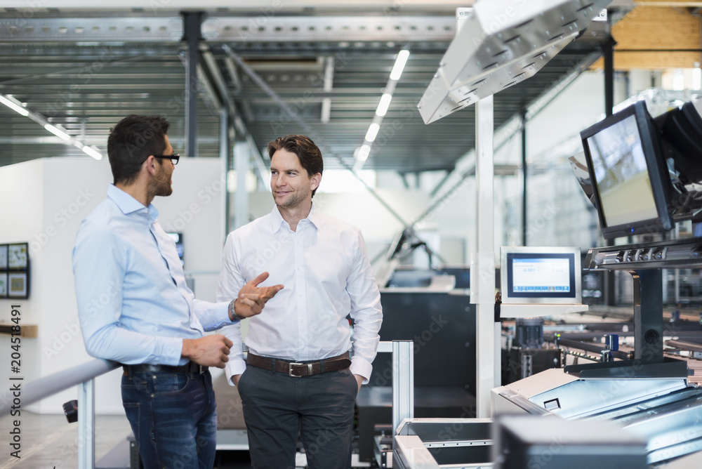 Two businessmen talking in modern factory Two businessmen talking in modern factory