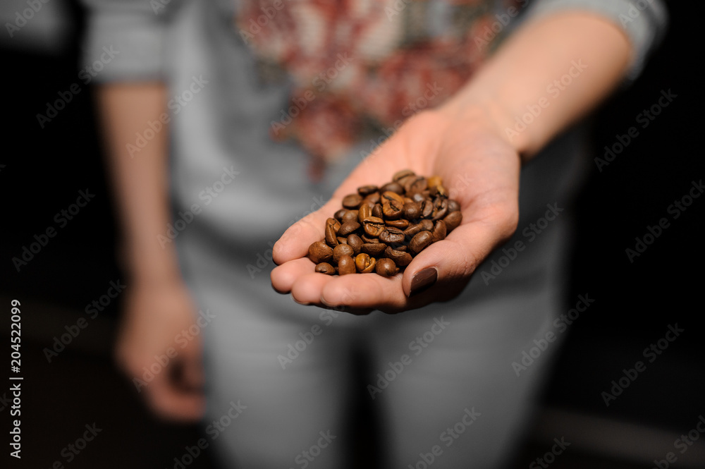 Female handd holding a handful of fresh coffee beans Female handd holding a handful of fresh coffee beans