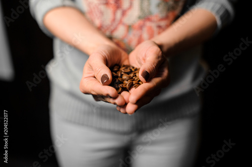 Female hands holding a handful of fresh coffee beans