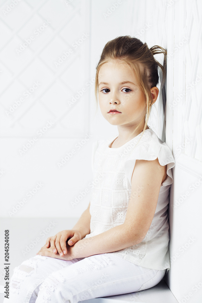 Children's fashion. Beautiful pensive serious blonde girl in white clothes. Fashion, lifestyle and people concept. Children's fashion. Beautiful pensive serious blonde girl in white clothes. Fashion, lifestyle and people concept.