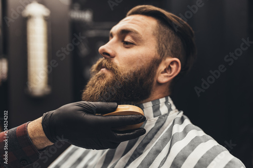 Leinwand Poster Hipster young good looking man visiting barber shop