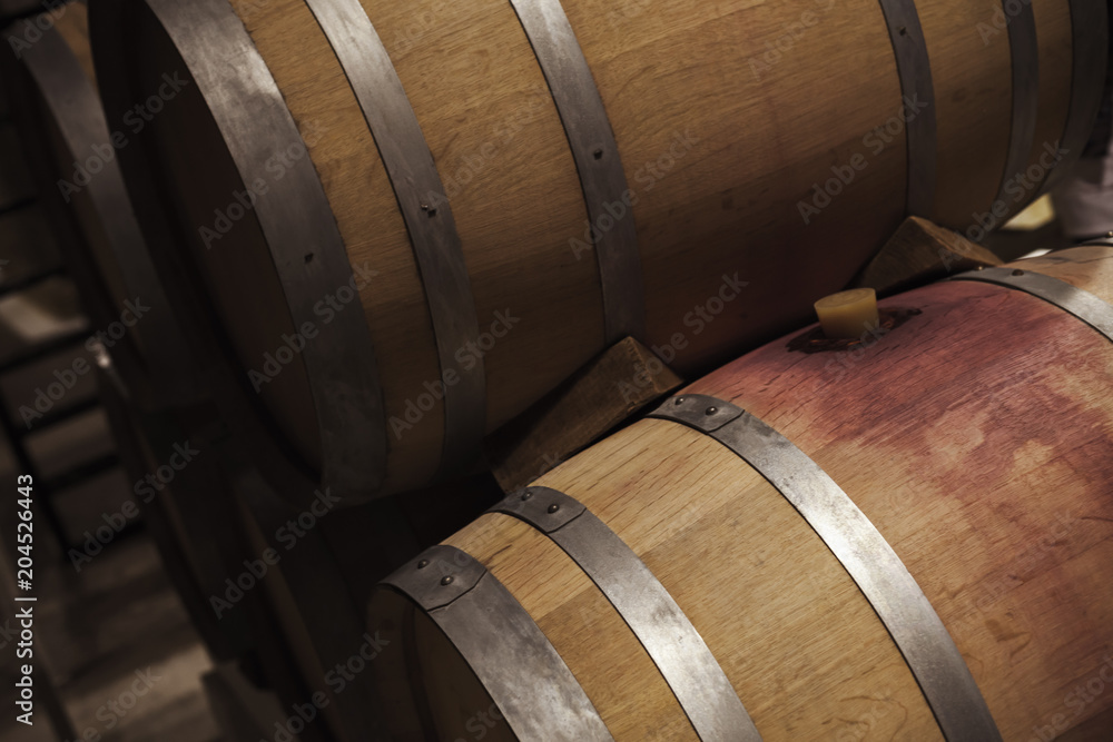 Wooden barrels with red wine in dark winery