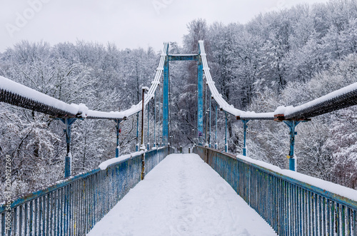 Cable-stayed old bridge covered with snow. Blue bridge in winter. photo