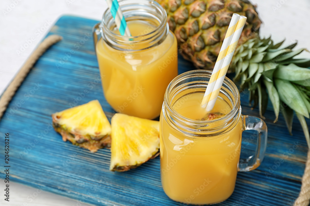 Mason jars with delicious pineapple juice on tray Mason jars with delicious pineapple juice on tray