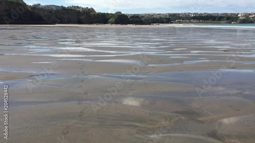 Dramatic Cliffs rise from the wet sand as the tide rushes in to the shore (4K)