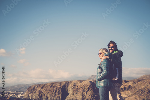 Mother with white hair and a 45 year old son spend time together smiling, surrounded by unspoiled nature. Between sea and mountain