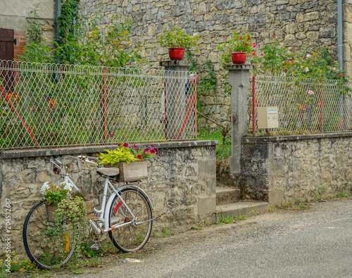 Feneyrols, Midi Pyrenees, France - July 23, 2017: Decorative bicycle with flowers resting on a rustic village facade