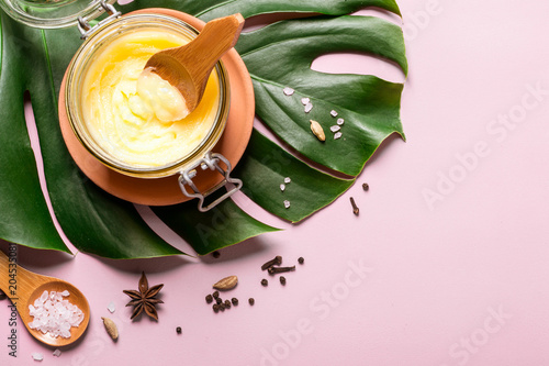 ghee butter in a glass jar, pink salt and spices on pink background photo