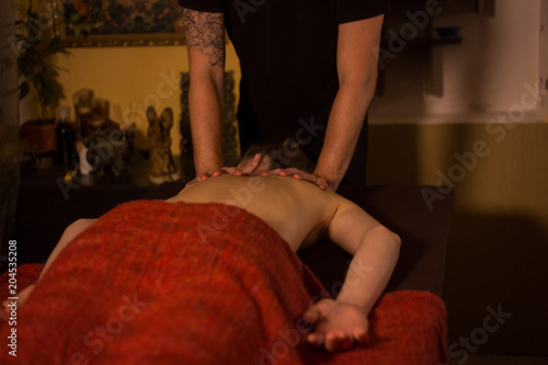 Masseur hands doing massage in spa center, studio. Warm romantic illumination, low key. Wellness, relaxation and healthcare concept