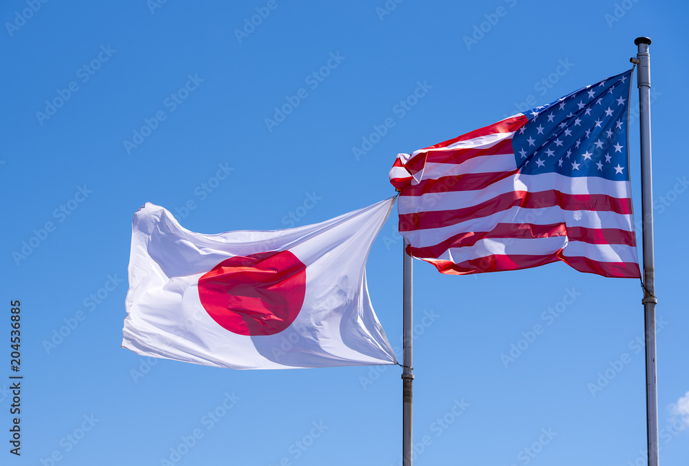 Naklejka premium American and Japanese Flags waving against blue Sky