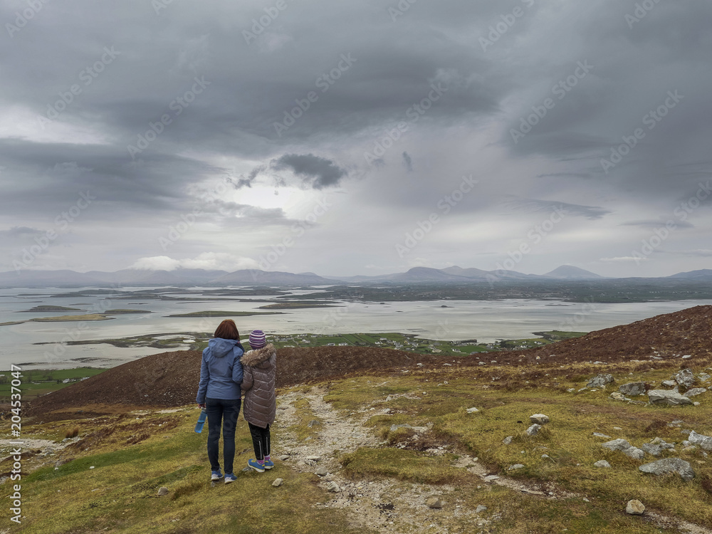 Mother and daughter taking in beautiful view from Croagh Patrick trail, Ireland county Mayo. Concept travel, memory, trip, adventure.
