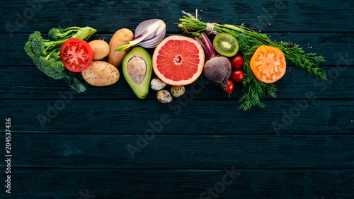 Healthy food. Vegetables and fruits. On a black wooden background. Top view. Copy space.