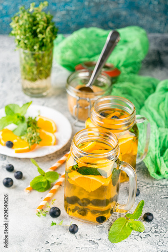 Orange Blueberry Detox Water or lemonade with mint in glass jar on ligth table