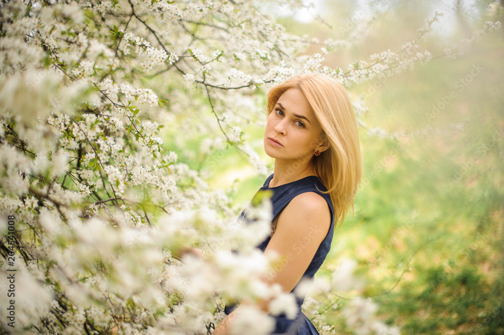 Beautiful girl standing between branches of white blossom tree Beautiful girl standing between branches of white blossom tree