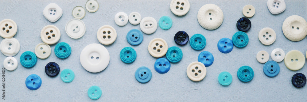 Bright multicolored buttons on a blue textured paper background, top view, flat lay. Beautiful abstract background. The concept of needlework, handmade. Bright multicolored buttons on a blue textured paper background, top view, flat lay. Beautiful abstract background. The concept of needlework, handmade.