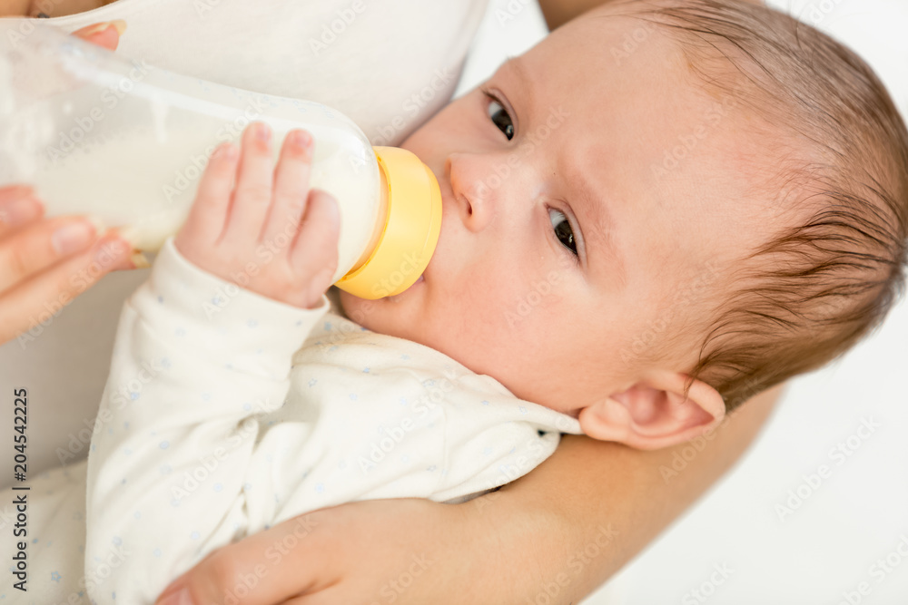 Closeup portrait of 3 months old baby boy holdin bottle with milk and eating Closeup portrait of 3 months old baby boy holdin bottle with milk and eating