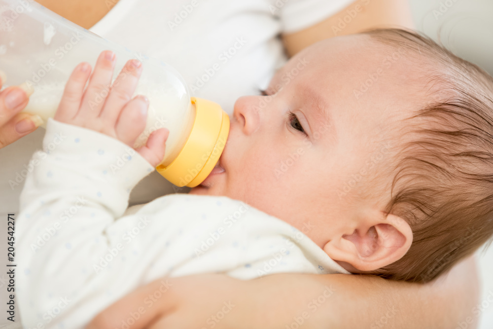 Closeup portrait of adorable baby boy sucking milk from bottle Closeup portrait of adorable baby boy sucking milk from bottle