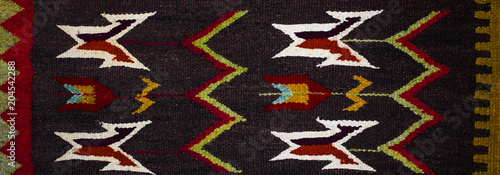 Close up of geometric patterned carpet. Hand woven rug with red, yellow, blue and other colors. Hand woven carpet with abstract design. Colorful carpet. Textile background. Abstract background.