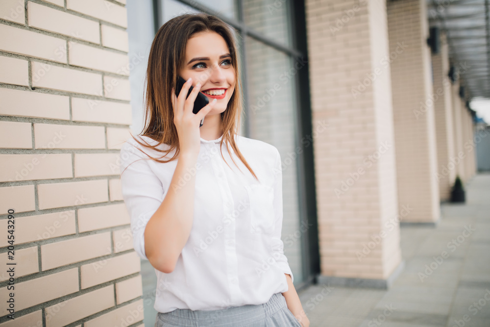 Happy woman on the phone in the city. Smiling woman talking on mobile phone in front of building. Happy woman on the phone in the city. Smiling woman talking on mobile phone in front of building.