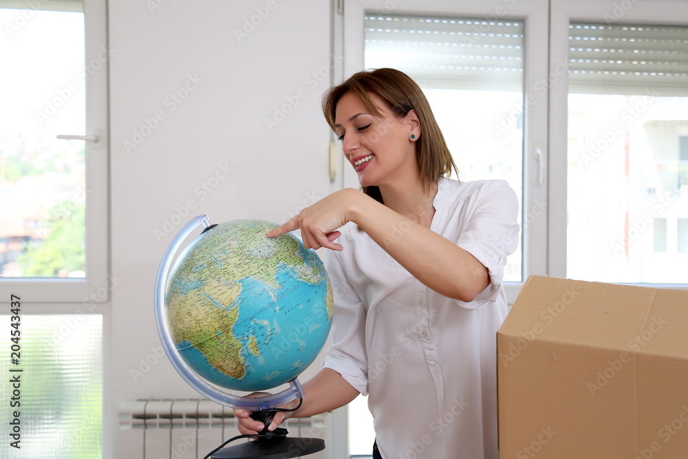 A young woman looking at a map of the world in a new apartment A young woman looking at a map of the world in a new apartment