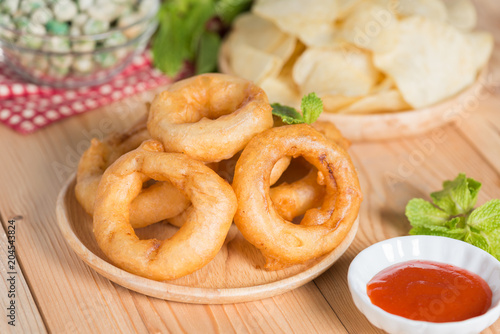 Fried onion rings , potato chips and green nuts. Snacks food.