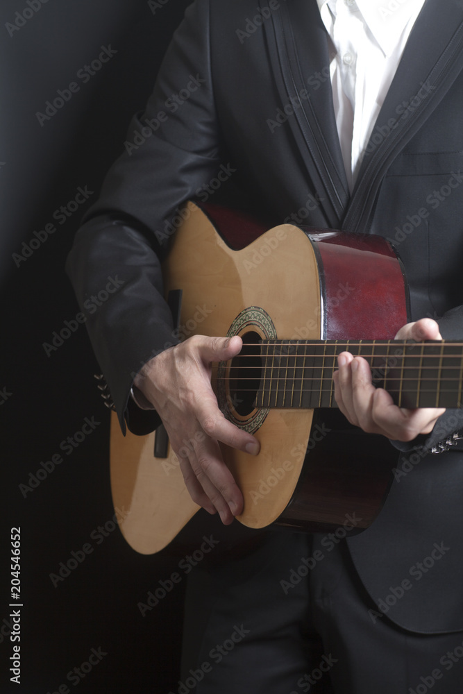 Man in black suit with acoustic classic guitar Man in black suit with acoustic classic guitar