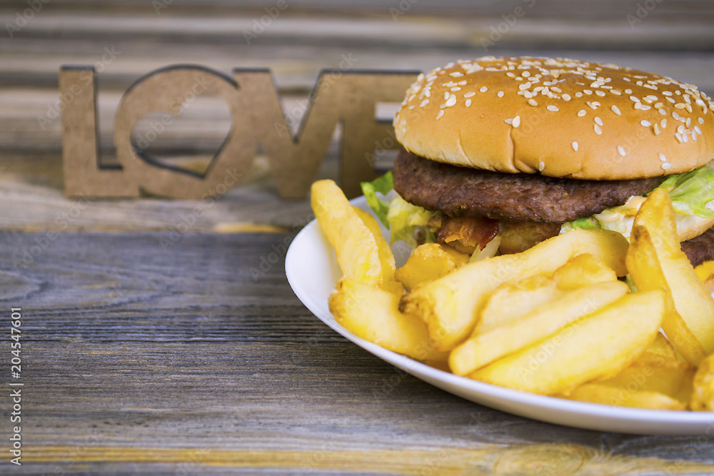 fast food hamburger with french fries on an old wooden background