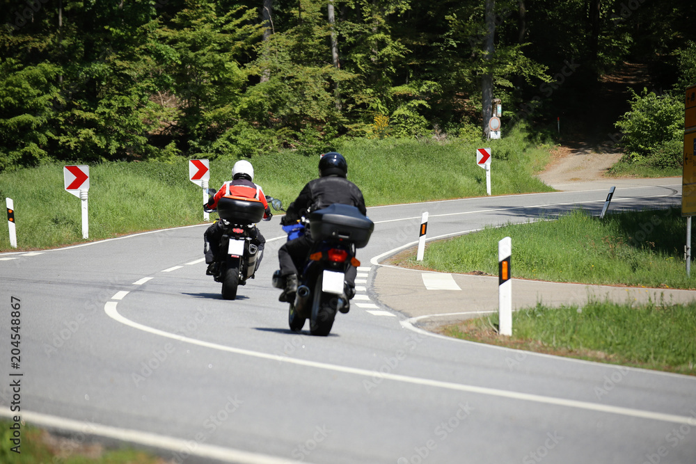 Gruppe von Motorradfahrern auf einer kurvenreichen Landstraße
