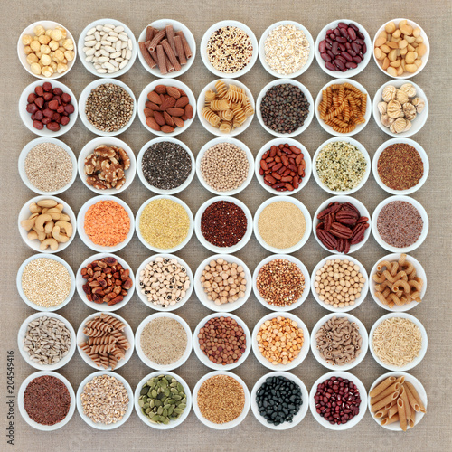 Vegan high protein dried health food collection with nuts, seeds, legumes, pasta, grains and cereals. Foods high in fibre, antioxidants, anthocyanins, vitamins and minerals. Top view on hessian.