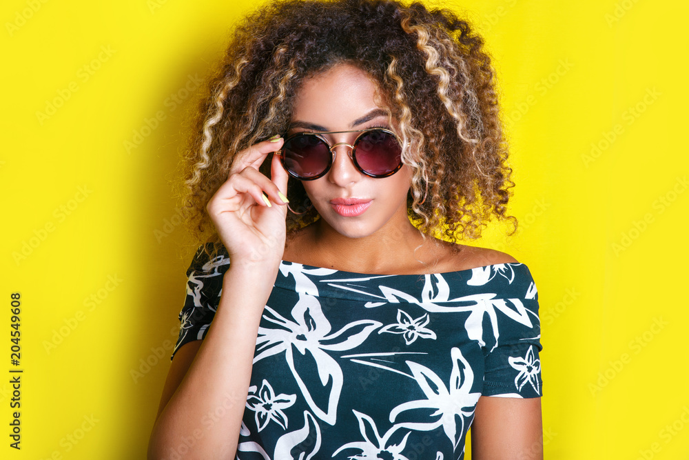 Beauty portrait of young african american girl with afro hairstyle. Girl posing on yellow background, looking at camera. Studio shot. Beauty portrait of young african american girl with afro hairstyle. Girl posing on yellow background, looking at camera. Studio shot.
