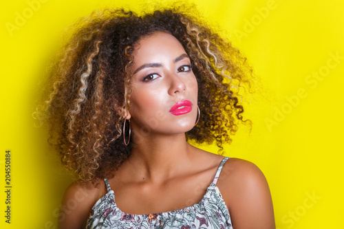 Beauty portrait of young african american girl with afro hairstyle. Girl posing on yellow background, © Elena Kratovich
