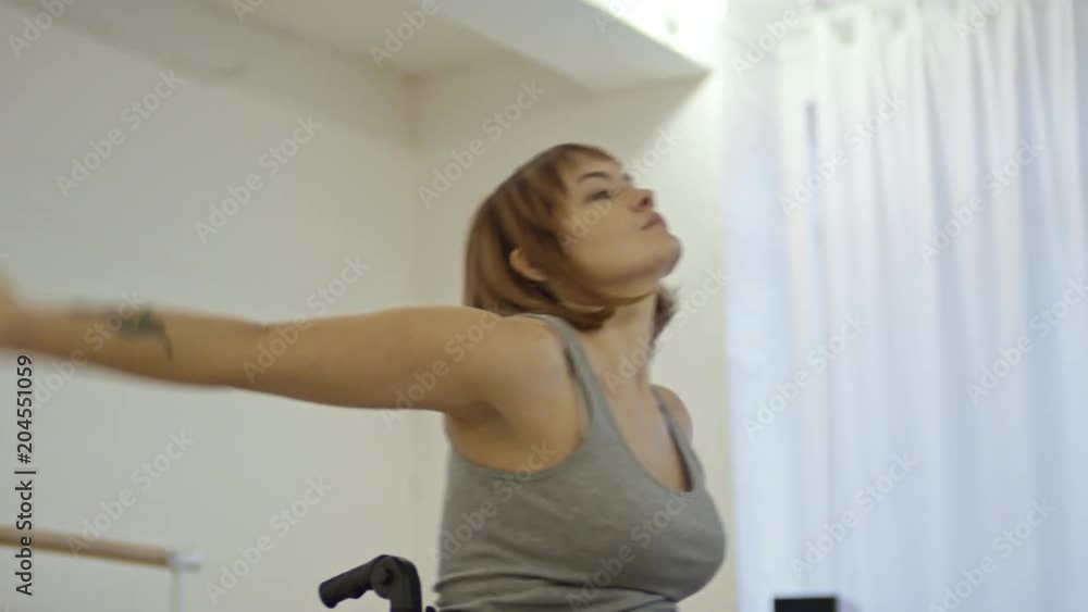 Young attractive woman in wheelchair moving arms while learning dance in studio Young attractive woman in wheelchair moving arms while learning dance in studio